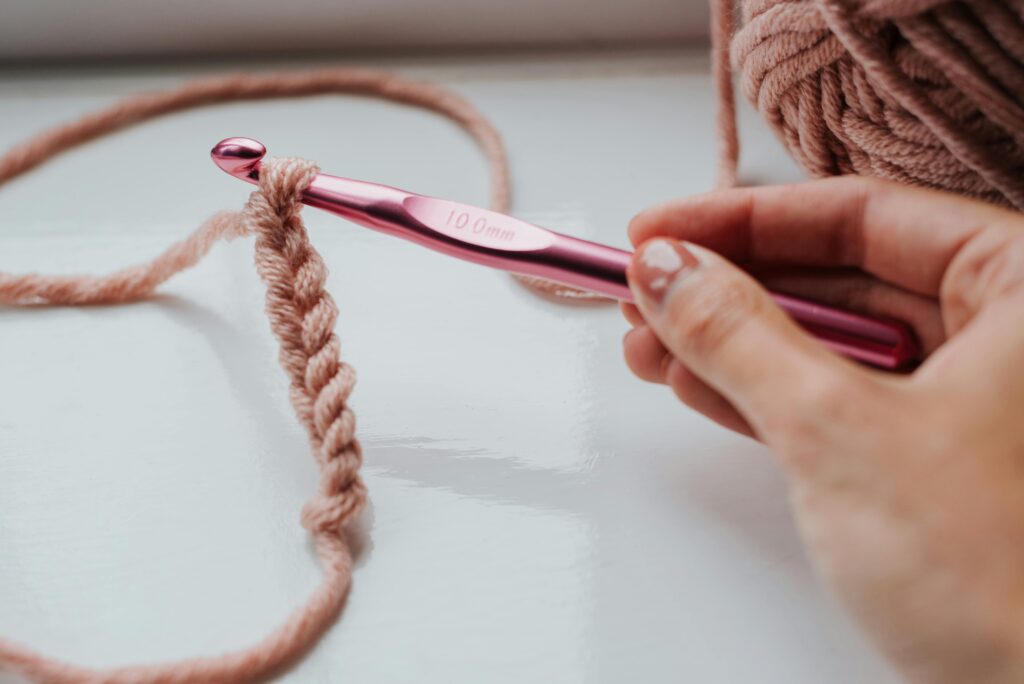 person crocheting with a pink 10mm crochet hook and pink yarn